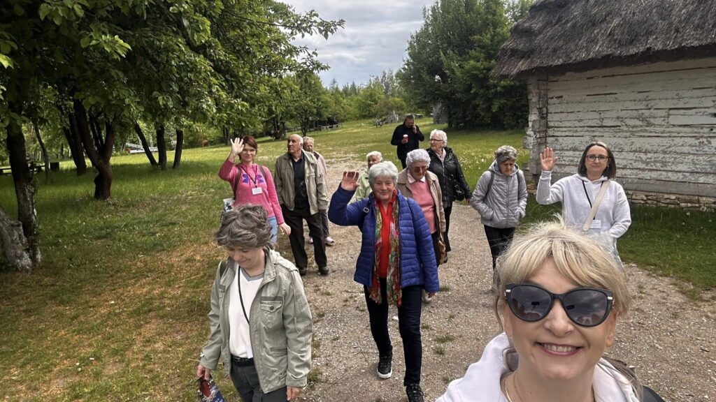 Zdjęcie przedstawia uczestników wycieczki spacerujących po terenie skansenu wsi kieleckiej.