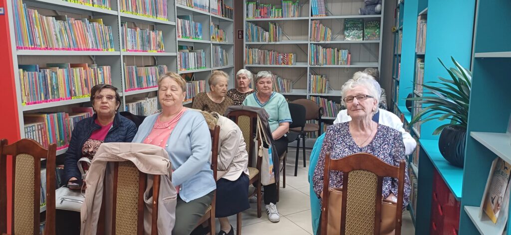 Zdjęcie przedstawia uczestników Domu Seniora słuchających wierszy Piotra Pilarskiego w Bibliotece Miejskiej w Wolbromiu